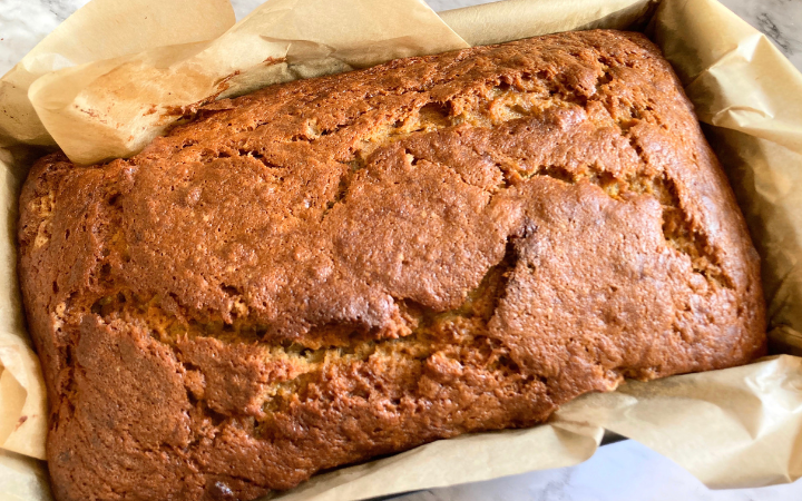 banana bread in a loaf pan lined with parchment